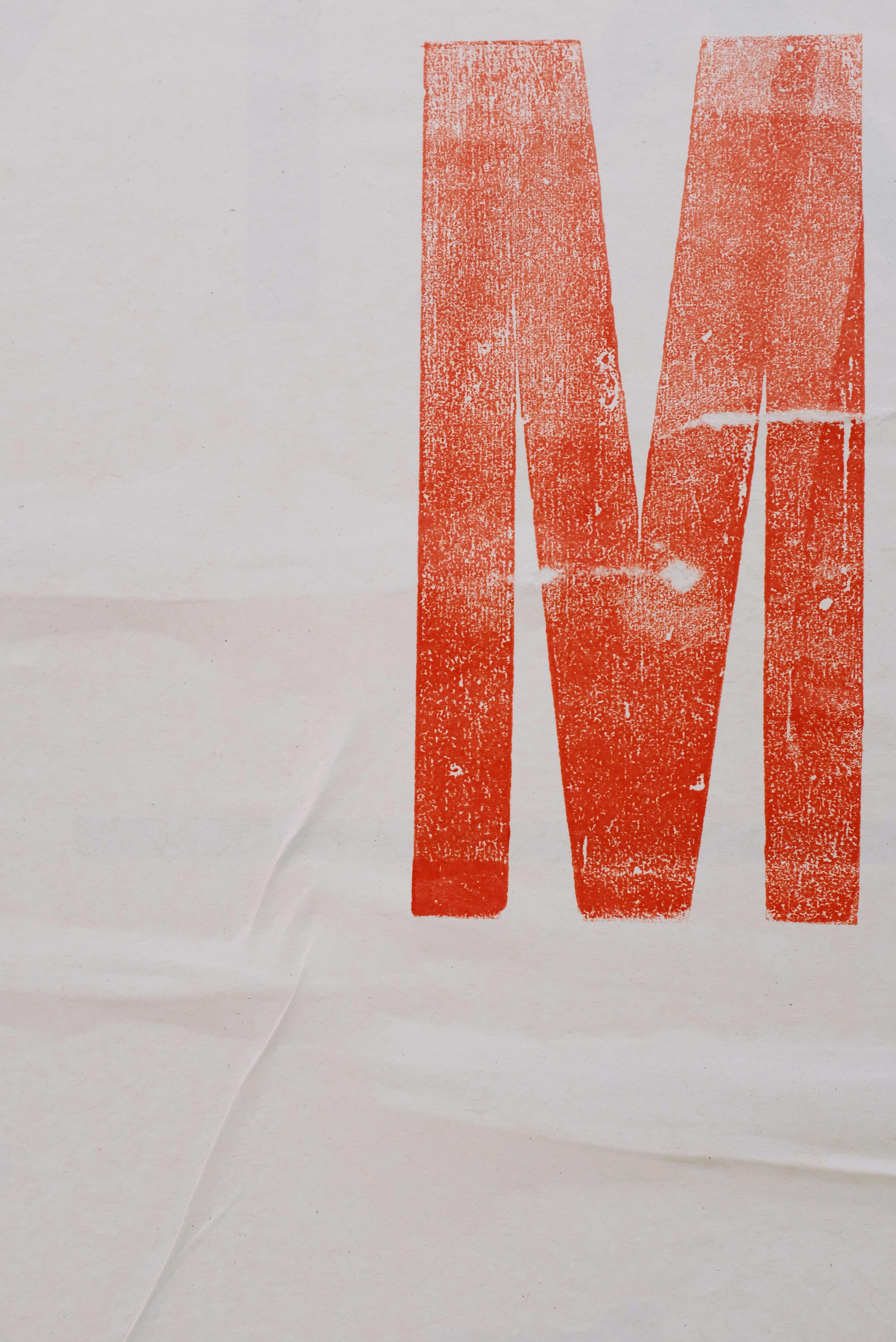 A bold, oversized red letter M block-printed on textured paper - confident hand-crafted typography