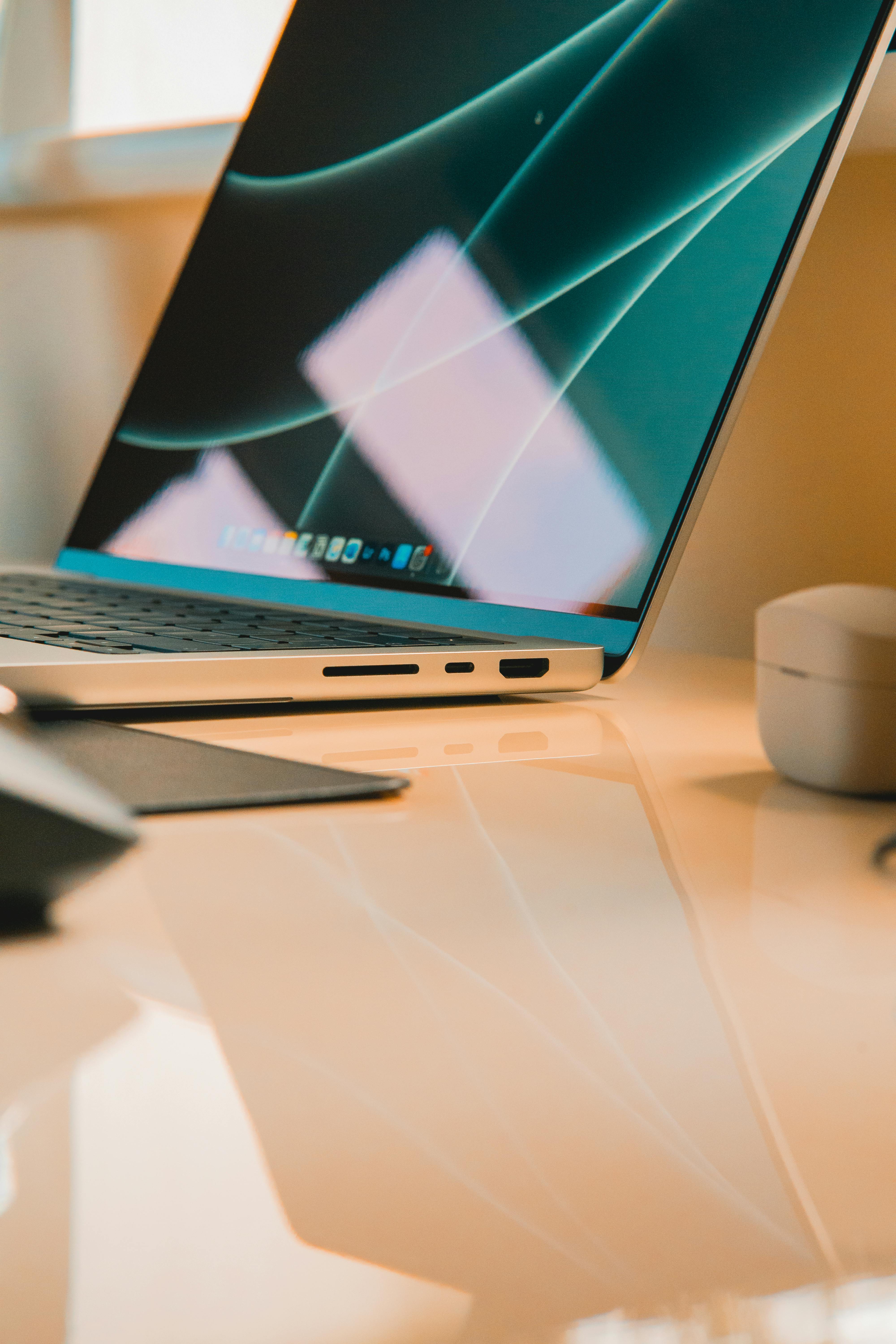 A minimal MacBook on a clean reflective desk in warm light - clean, considered workspace